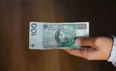 Banknot o nominale 100 złotych. Polski banknot trzymany w dłoni.