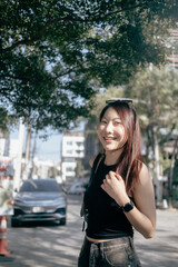 Fototapeta premium A woman wearing sunglasses and a black tank top is standing in front of a car