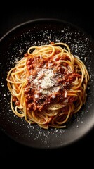 Homemade spaghetti topped with rich meat sauce and parmesan cheese served on a black plate