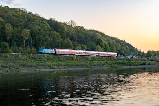 SAXON SWITZERLAND, GERMANY - 22. April 2025: VVO train next to the Elbe river in the Saxon Switzerland Landscape. The public transportation line S1 or S2 is also called S-Bahn and is red colored.