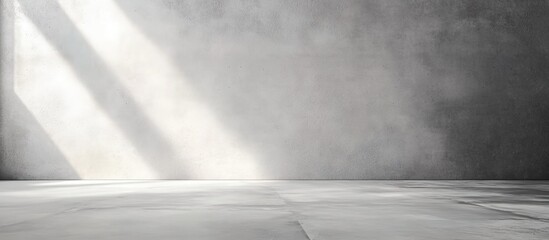 Empty gray cement-walled room with diagonal sunlight shadows.