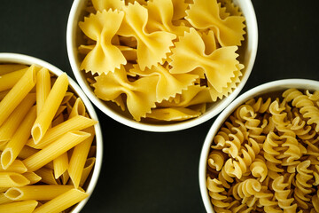  Three bowls of Healthy Farfalle, Penne and Fusilli Italian Pasta Ready to Cook