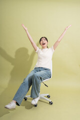 Joyful celebration of success with arms raised in the air seated on a rolling chair against a...