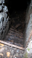 Fototapeta premium Dark, damp stone stairway descends into a dimly lit, subterranean passage