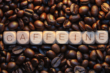 Wooden blocks spelling caffeine surrounded by roasted coffee beans