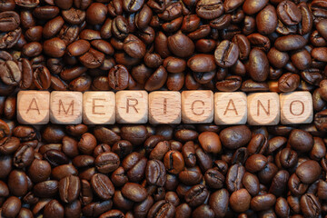Americano word on wooden blocks surrounded by roasted coffee beans