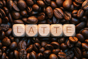 Wooden tiles spelling latte surrounded by coffee beans