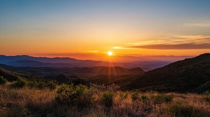 Obraz premium Majestic sunset over a vast, layered mountain range, casting long shadows and vibrant colors across the landscape. Golden hour light illuminates the desert flora in the foreground. : Generative AI