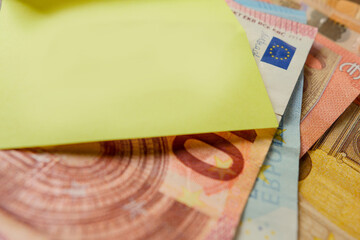 European banknotes on a wooden table and yellow paper note on top. Monthly bill payments for house rent, electricity, water and phone. Rising cost of living in Euro Union theme.