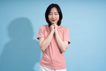 Woman expressing gratitude in a serene environment with a soft blue background during daytime