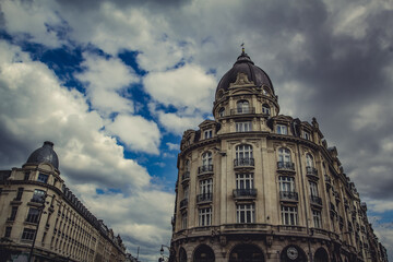 Ornate building featuring classic French urban architecture with rounded corner tower and topped...