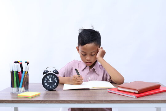 Thoughtful Asian schoolboy studying in the classroom. Isolated on white background