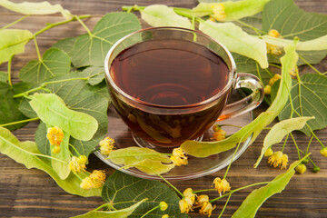 Cup of tea with linden flowers on a wooden table.
