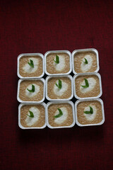 Cups of Bubur Merah Putih or Red and White porridge. Traditional Indonesian food made of sticky rice and brown sugar. Set on top of maroon fabrics. Selective focus. 