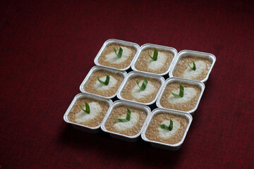 Cups of Bubur Merah Putih or Red and White porridge. Traditional Indonesian food made of sticky rice and brown sugar. Set on top of maroon fabrics. Selective focus. 