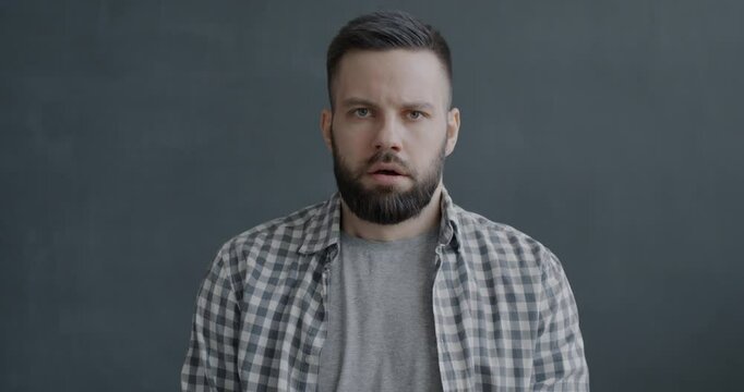 Slow motion portrait of shocked young man staring at camera speechless on black color background. Emotion and people concept.
