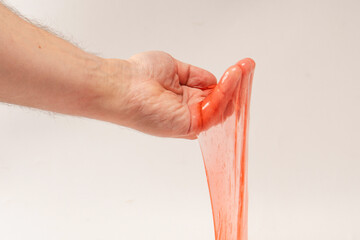 Red slime toy in man hand isolated on white.