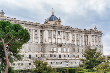 Fototapeta premium Madrid, Spain - 03.10.2025: Grand neoclassical architecture under a dramatic cloudy sky of the Royal Palace of Madrid.