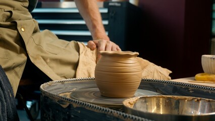 Potter man master sitting at studio craft craftsman pottery wheel spinning jug rotating ceramic cup clay workshop creating mug handmade hobby artist working handcraft male small business turning vase