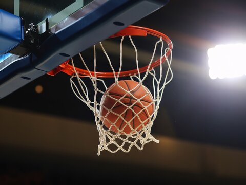 A basketball swishes through the net in a dynamic and thrilling game atmosphere.
