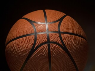 Close-up of a textured basketball against a dark background, emphasizing its detail and design.
