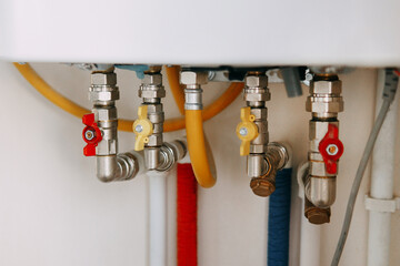 Close-up view of water heater pipes and valves in a utility room, featuring colorful connectors and...