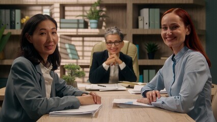 Three multiracial happy females business team businesswomen coworkers office girls group colleagues portrait Caucasian Asian women smiling posing partnership corporate together multiethnic briefing