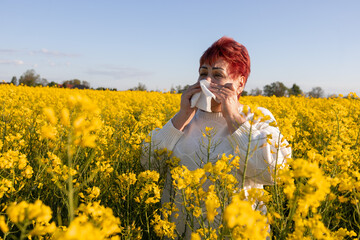 Fototapeta premium Mature woman with allergies is in a blooming field