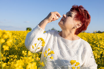 Mature woman suffering from flowering plant allergy is treated with nasal spray