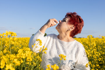 Mature woman suffering from flowering plant allergy is treated with nasal spray