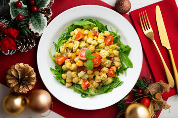 Mediterranean chickpea salad with avocados and vegetables. Top view table with christmas decorations.