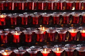 Lots of prayer candles in glass candlesticks.