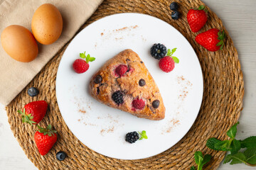 Triangular English scones with blackberries, raspberries and chocolate chips. Top view table with christmas decorations.