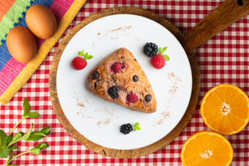 Triangular English scones with blackberries, raspberries and chocolate chips. Top view table with christmas decorations.