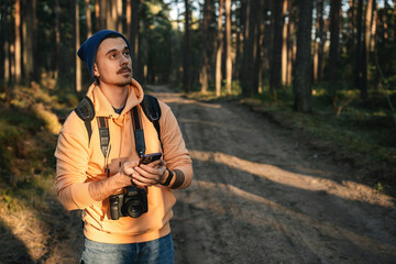 Man Using Smartphone GPS for Navigation in Forest with Camera Gear