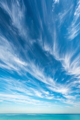 Stunning blue sky with wispy clouds above calm turquoise ocean water