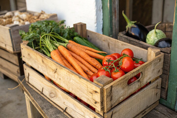 Freshly Harvested Organic Carrots, Tomatoes, and Cucumbers in Rustic Wooden Crate at Farmers Market