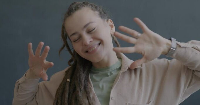 Slow motion portrait of joyful young woman with dreadlocks dancing having fun on black color background. People and entertainment concept.