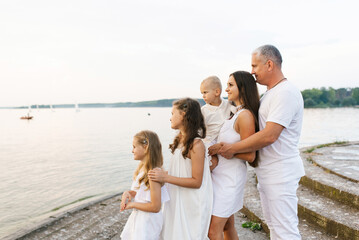 Obraz premium Happy family of five is standing on a pier overlooking the water