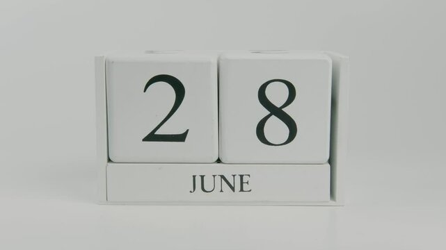 A hand flips a wooden calendar from June 28th to June 29th on a white background, symbolizing the flow of time