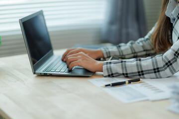 Professional female accountant reviewing annual expense reports at her desk with a laptop and paperwork — ideal for finance, tax, and corporate business themes.