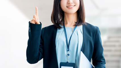 ノートパソコンを持って案内をする笑顔の女性・ビジネスウーマン