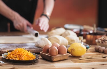 Baking cozonac for Easter unfolds with flour, eggs, and other ingredients on a textured wooden surface, highlighting family traditions and the love of homemade treats, all in soft natural light
