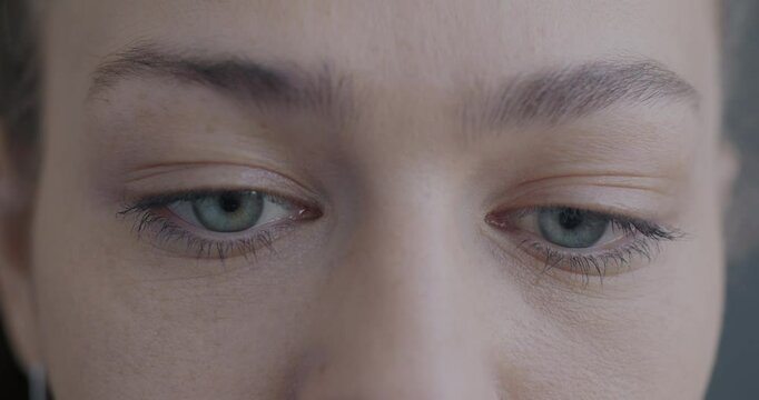 Close-up slow motion portrait of upset young woman's eyes looking at camera while lady feeling sad and confused. People and emotion concept.