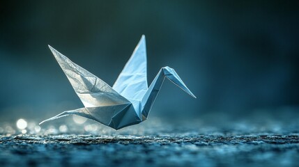 Light blue origami crane poised in mid-flight against a dark background. Detailed folds and elegant form