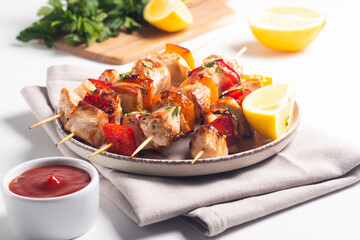 Delicious grilled chicken skewers with capsicum, lemon, salad and ketchup on a plate over the table. Chicken kebab. Healthy food concept.