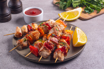 Delicious grilled chicken skewers with capsicum, lemon, salad and ketchup on a plate over the table. Chicken kebab. Healthy food concept.
