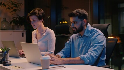 Professional team co-workers multiracial business man woman in dark night office typing laptops...