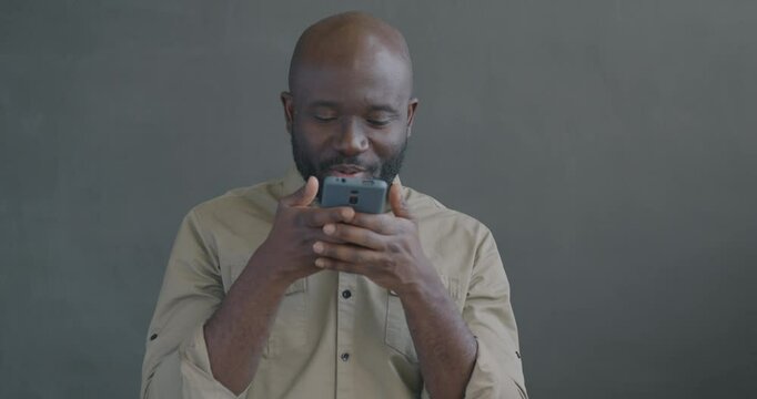 African American man messaging with smartphone sending audio message texting on black color background. People and communication concept.
