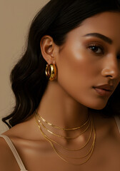 Close-up of a woman wearing gold hoop earrings and layered necklaces.